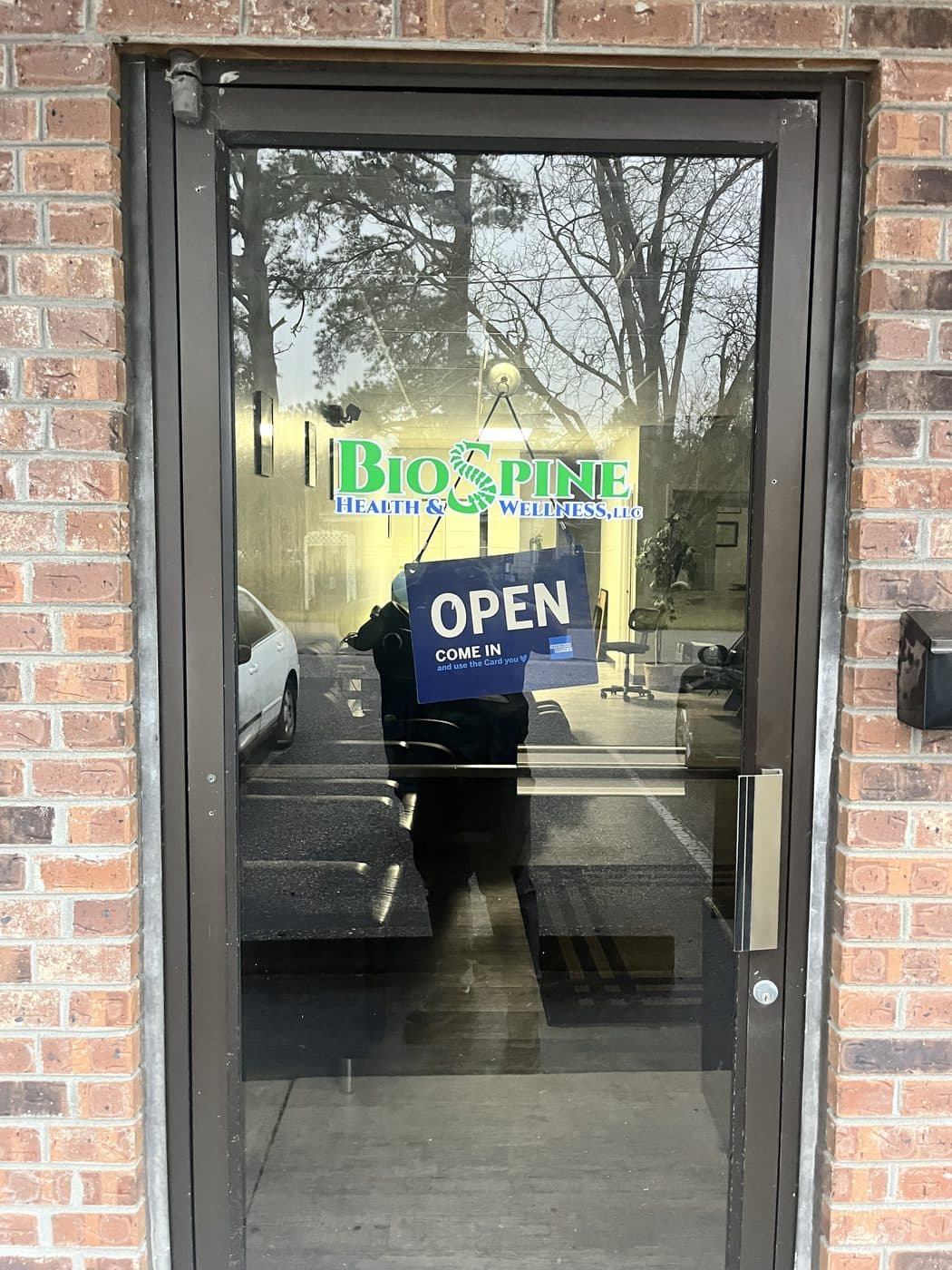 Front entrance of BioSpine Health and Wellness at 214 John St, Lake City, SC 29560, with the logo on the glass door and an open sign