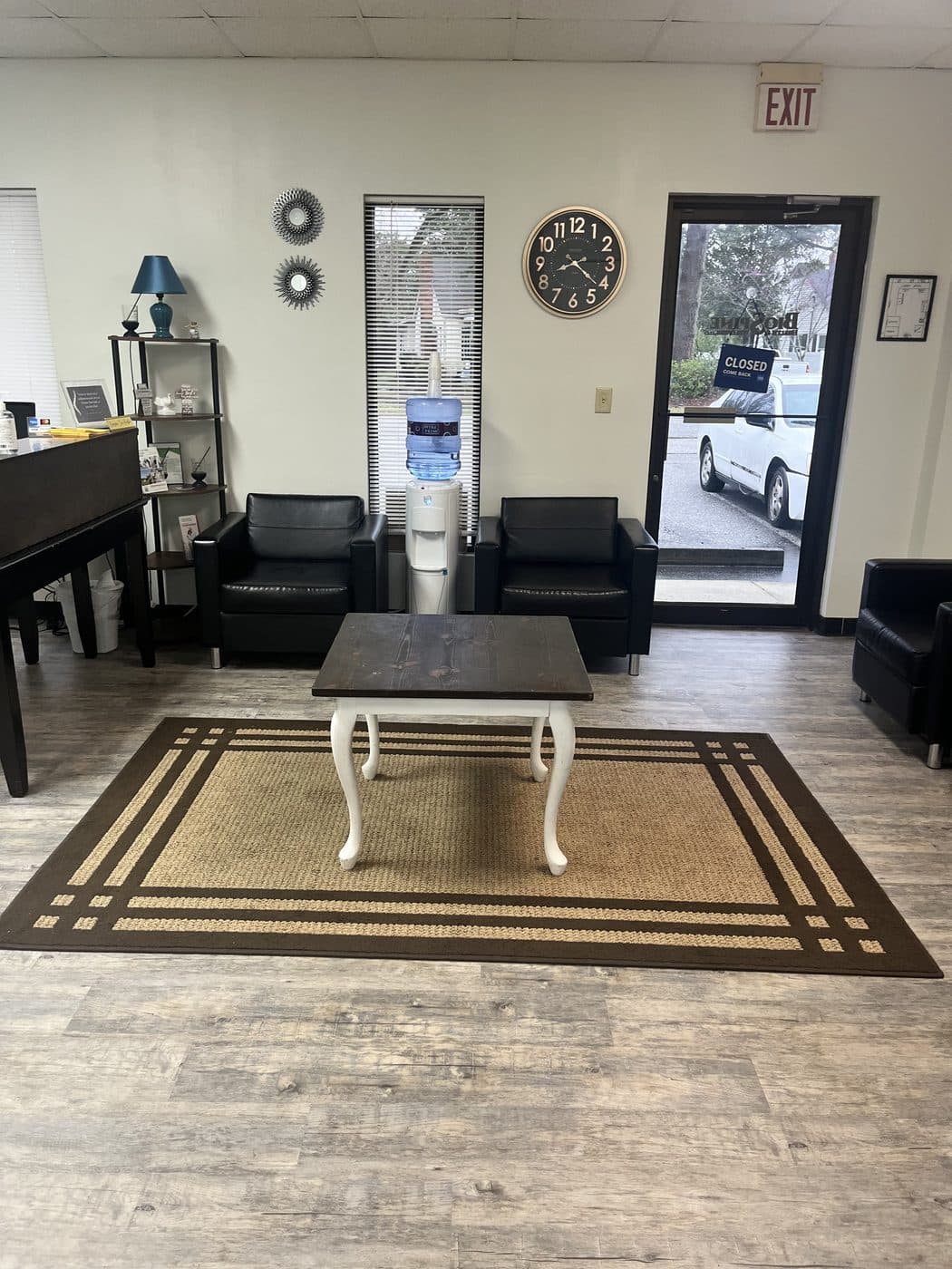 Waiting room at BioSpine Health and Wellness with armchairs, a coffee table, and a water cooler